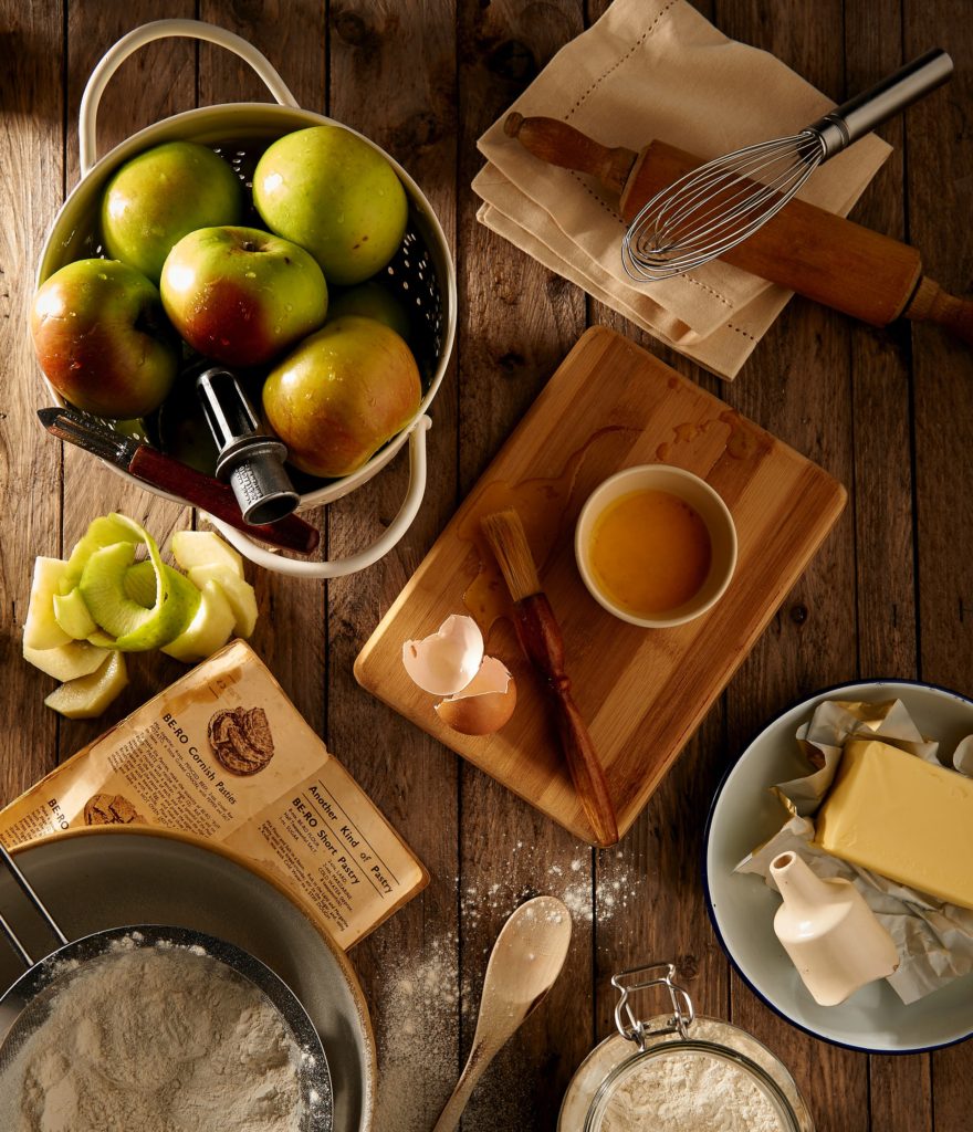 Baking tools, flour, butter and apples on a table.