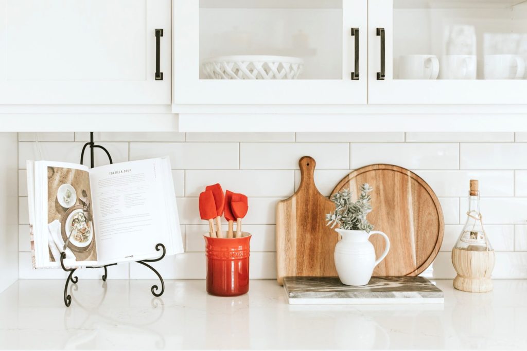 White kitchen counter top with wooden board, ladle, and book