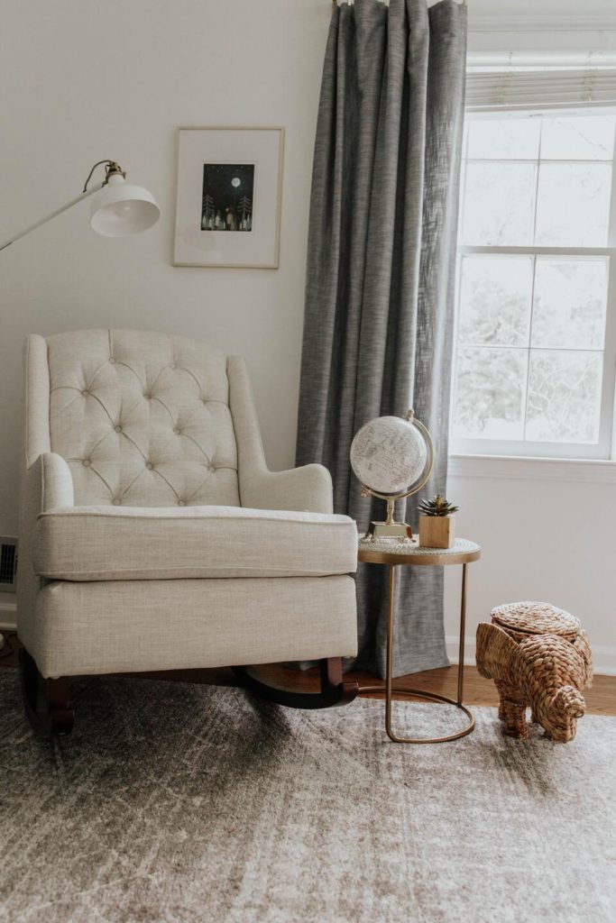 Cute wicker elephant beside a white sofa chair.