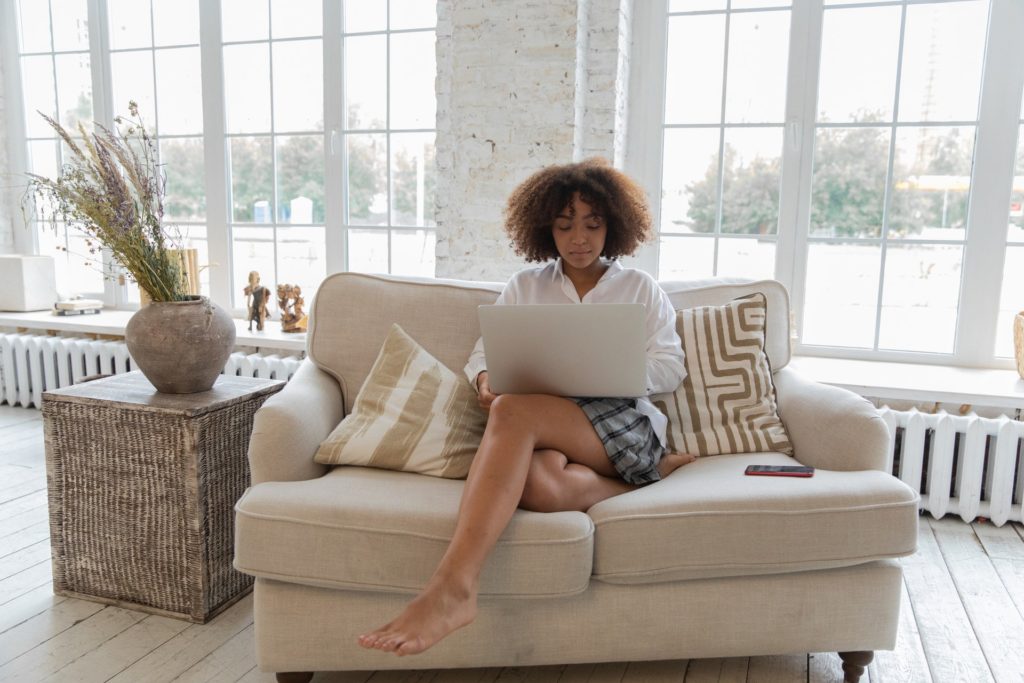 Lady sitting in a sofa beside a wicker side table.