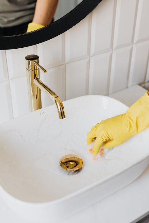 Cleaning the bathroom sink with soap and sponge