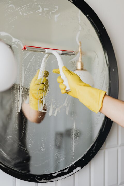 Cleaning the bathroom mirror with soap and a squeegee