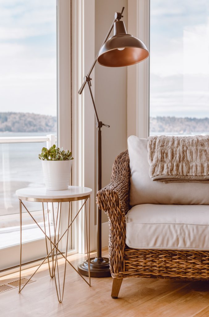 Comfortable wicker chair, brass side table, and brass adjustable lamp.