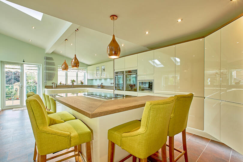 Modern kitchen with yellow green chairs.