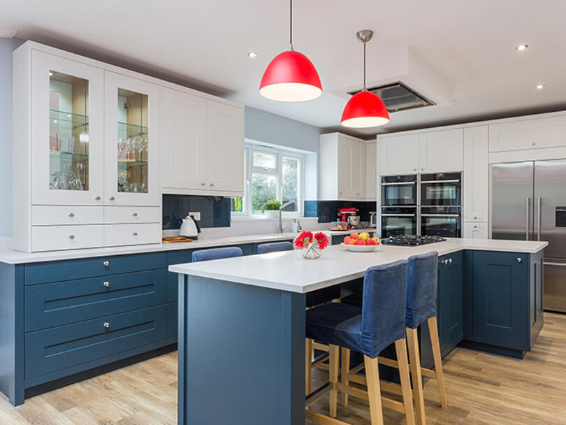 Blue and white kitchen with bright red pendant lights. 