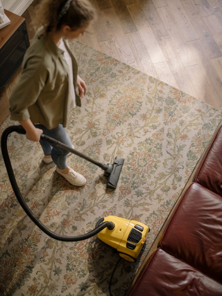 A lady cleaning the carpet using a vacuum cleaner