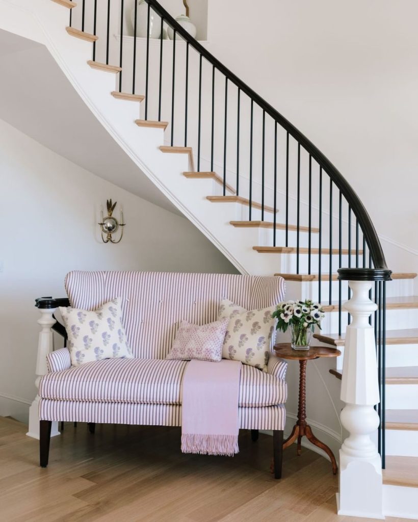 A striped pink sofa underneath the stairs. 