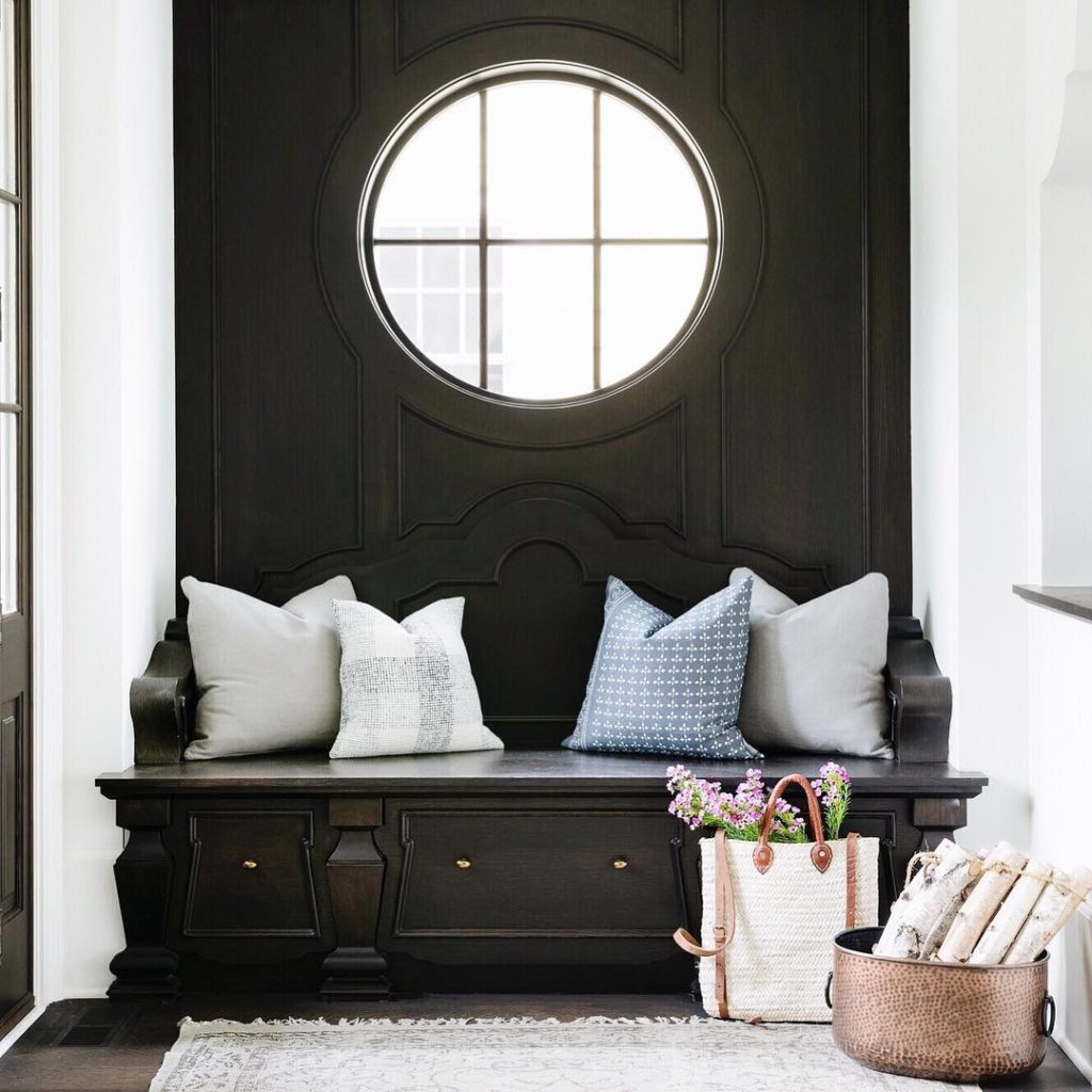 Black and white entryway with intricate detailing of wood paneling on a wall and crown molding 