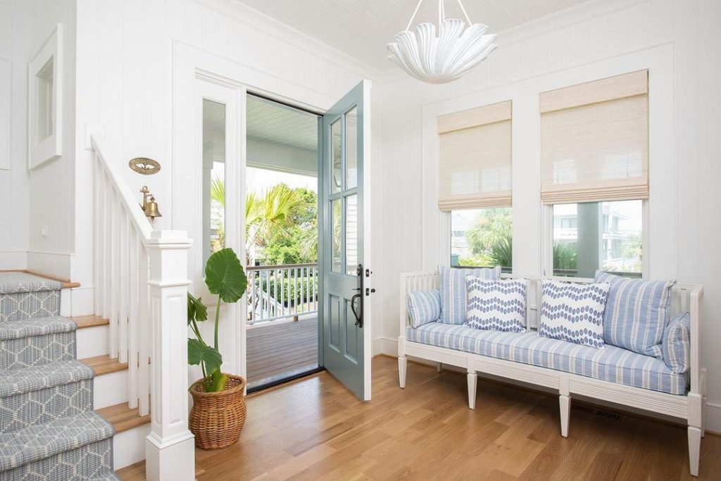 Coastal style of foyer or entryway with seashell-shaped chandelier, pale blue pillows and throws. 