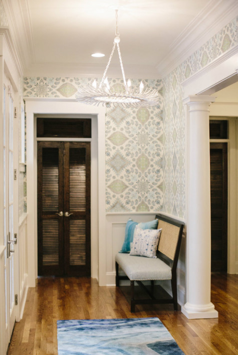 Small bench in an entryway or foyer. The entryway or foyer is also covered with wallpaper.