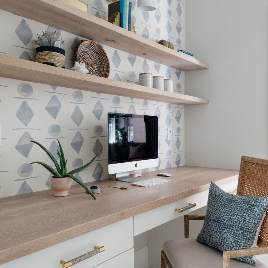 Beautiful home office with wallpaper, shelves, and drawers.